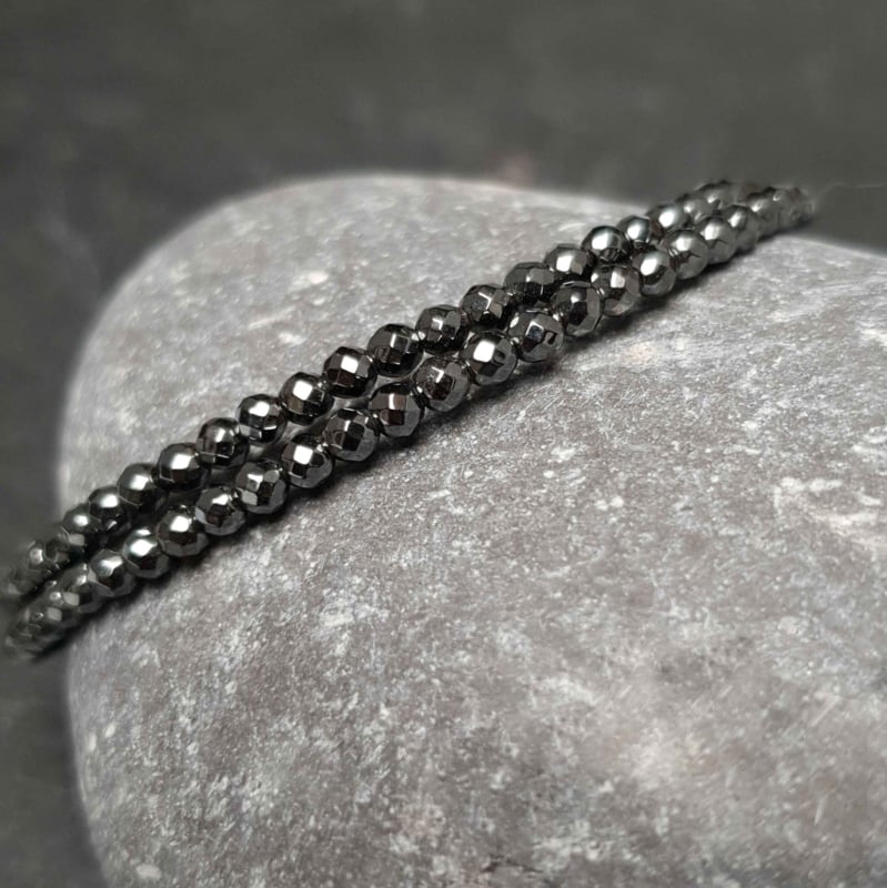 Zwart edelstenen wikkel armband met hematiet liggend op kei | Cadeau set Hematite