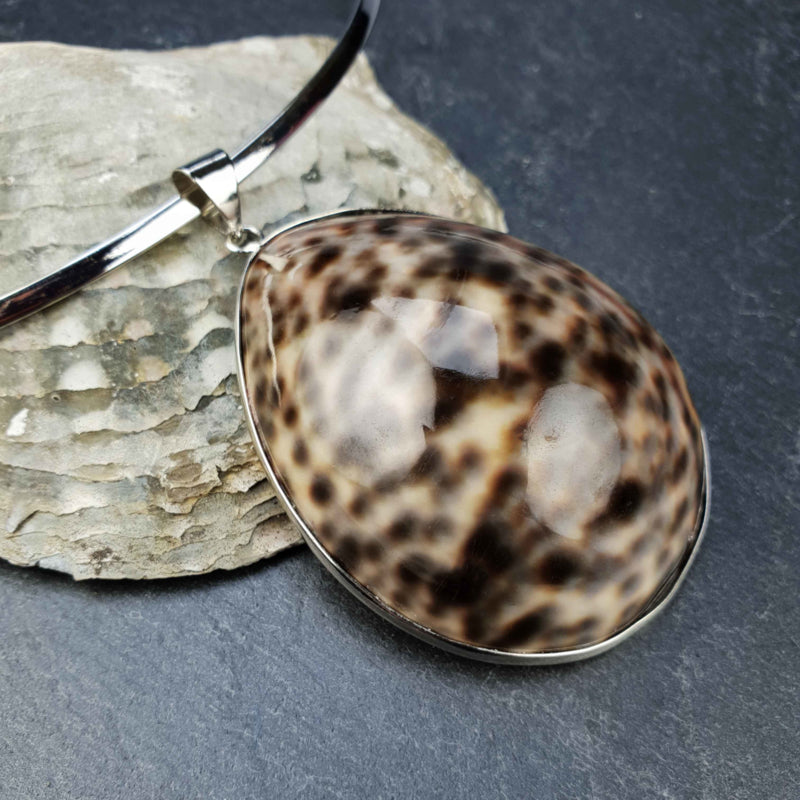 Detail van schelpen choker ketting met een bruin gespikkelde panter schelp liggend op leisteen | Panther
