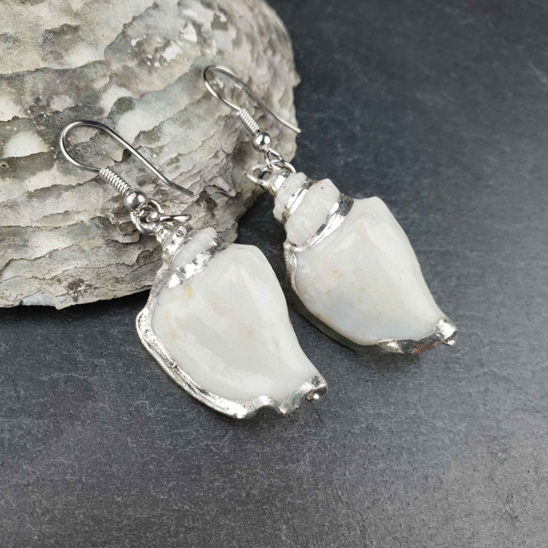 Schelp oorbellen met witte schelp en sterling zilver (925) liggend op leisteen | White Calau Shell Silver