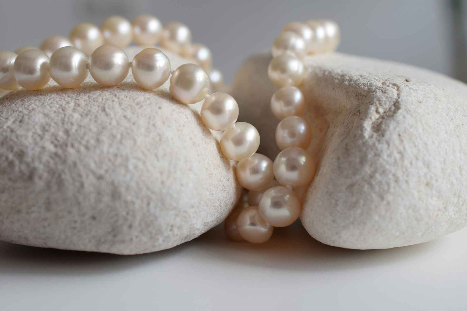 Witte parelketting liggend op witte stenen