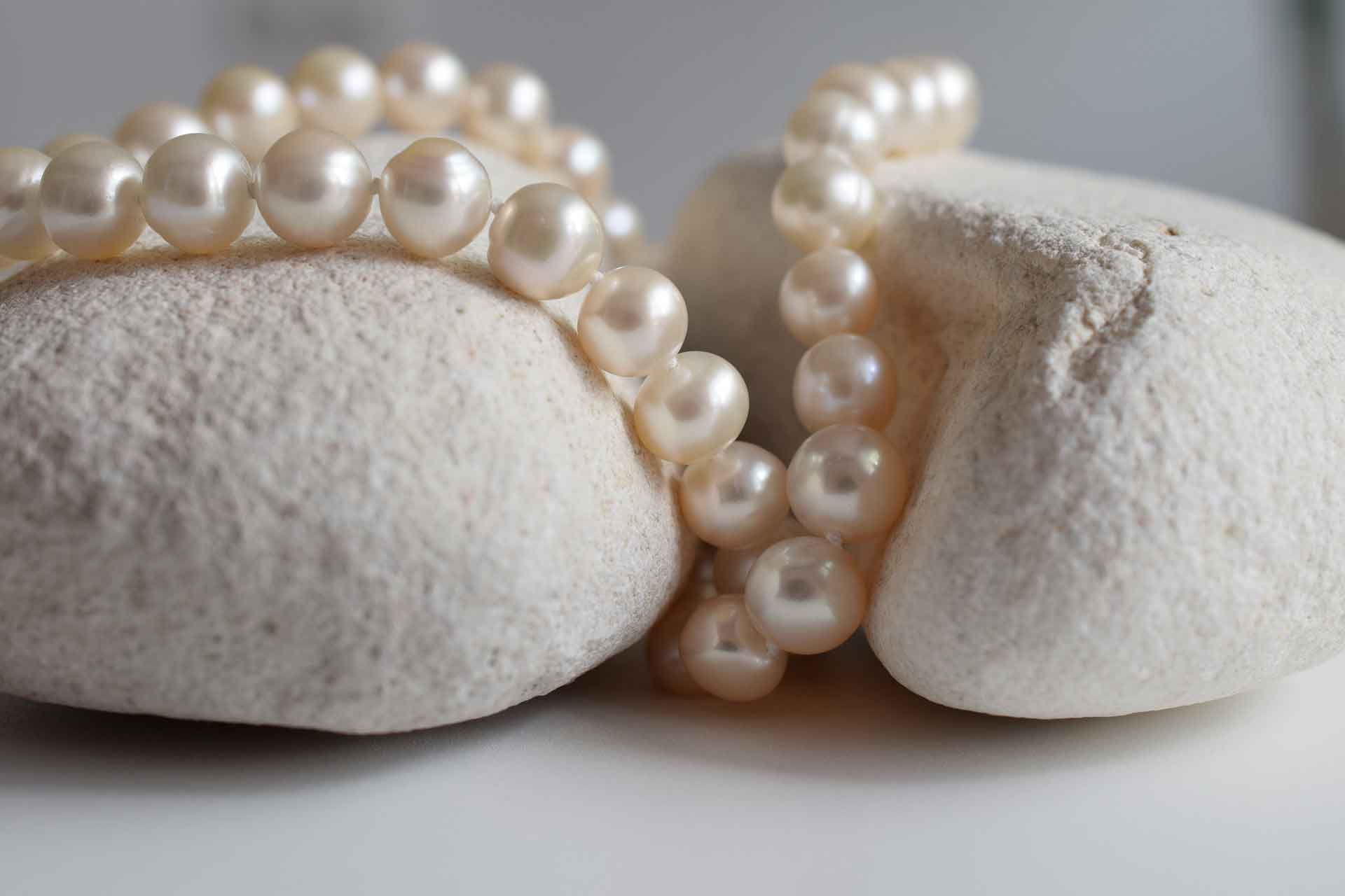 Witte parelketting liggend op witte stenen