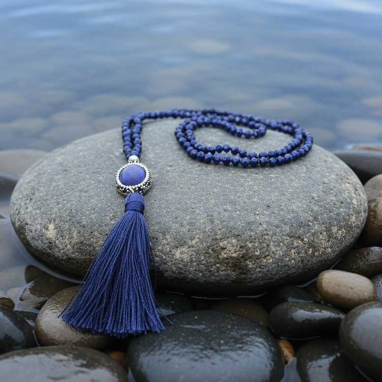 Lange blauwe handgeknoopte edelstenen ketting met lapis lazuli, stras steentjes en kwastje ligt op een steen in het water | Bright Lapis Lazuli Tassel