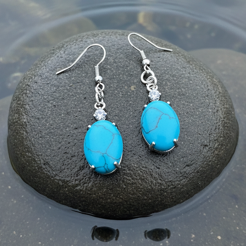 Blauw edelstenen oorbellen met turkoois, stras steentje en sterling zilver (925) liggend op steen in water | Turquoise Oval