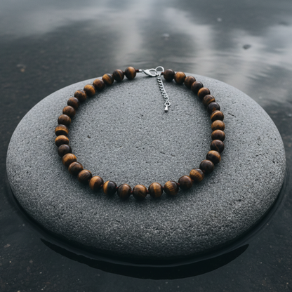 Bruine handgeknoopte edelstenen ketting met tijgeroog en sterling zilver (925)liggend op steen in water | Tiger Eye Ball