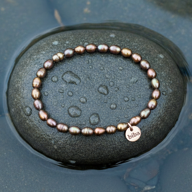 Bruin zoetwater parel armband, elastisch liggend op steen in water bovenaanzicht | Biba Brown Rice Pearl