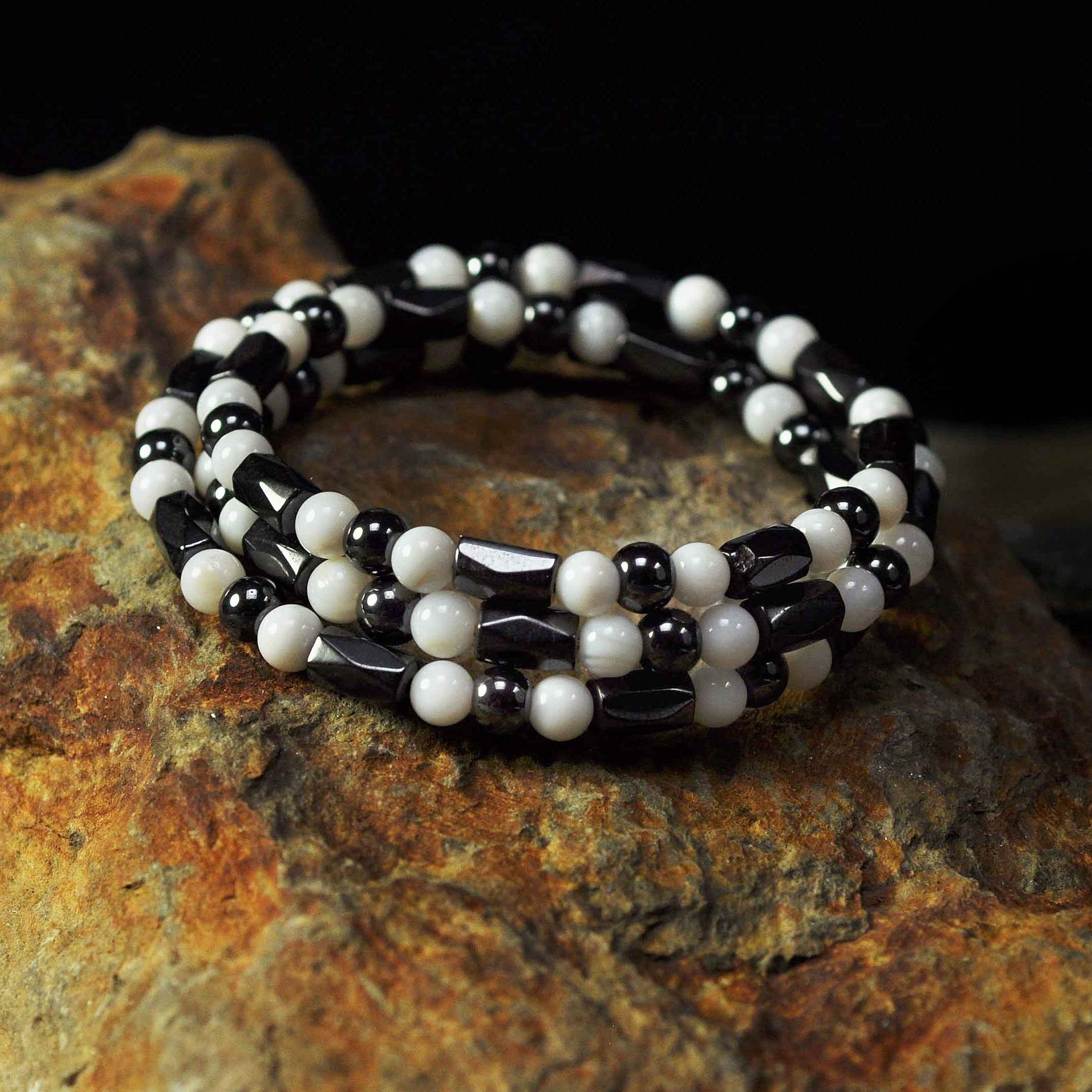 Edelstenen wikkel armband met magnetiet en parelmoer liggend op steen | Magnetite Shell Wrap