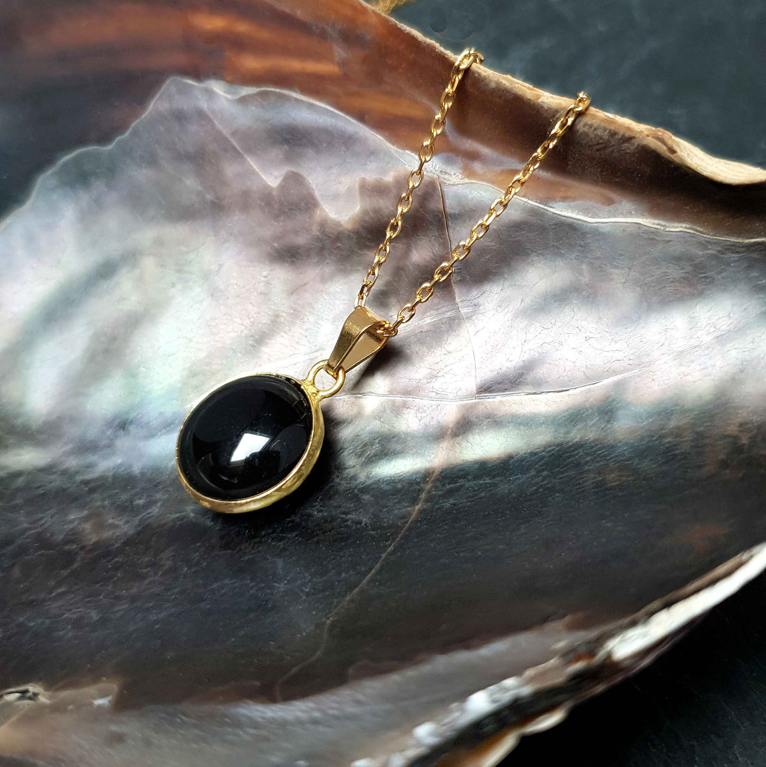 Zwarte edelstenen ketting met agaat en goud edelstaal liggend in schelp zijaanzicht | Black Agate Gold Round