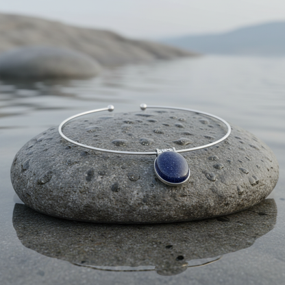 Zwart blauwe edelstenen ketting met ovale goudsteen hanger liggend op steen | Blue Goldstone Oval
