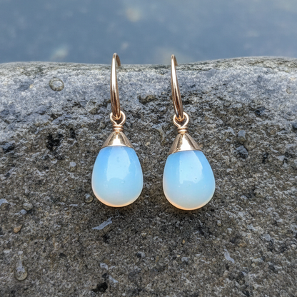 Blauwe edelstenen oorbellen met opaal liggend op steen | Gold Dip Sea Opal