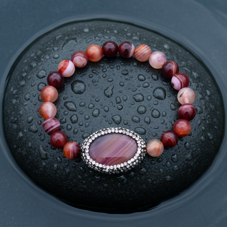 Rood edelstenen armband met agaat en stras steentjes liggend op steen in water, elastisch | Bling Oval Red Striped Agate