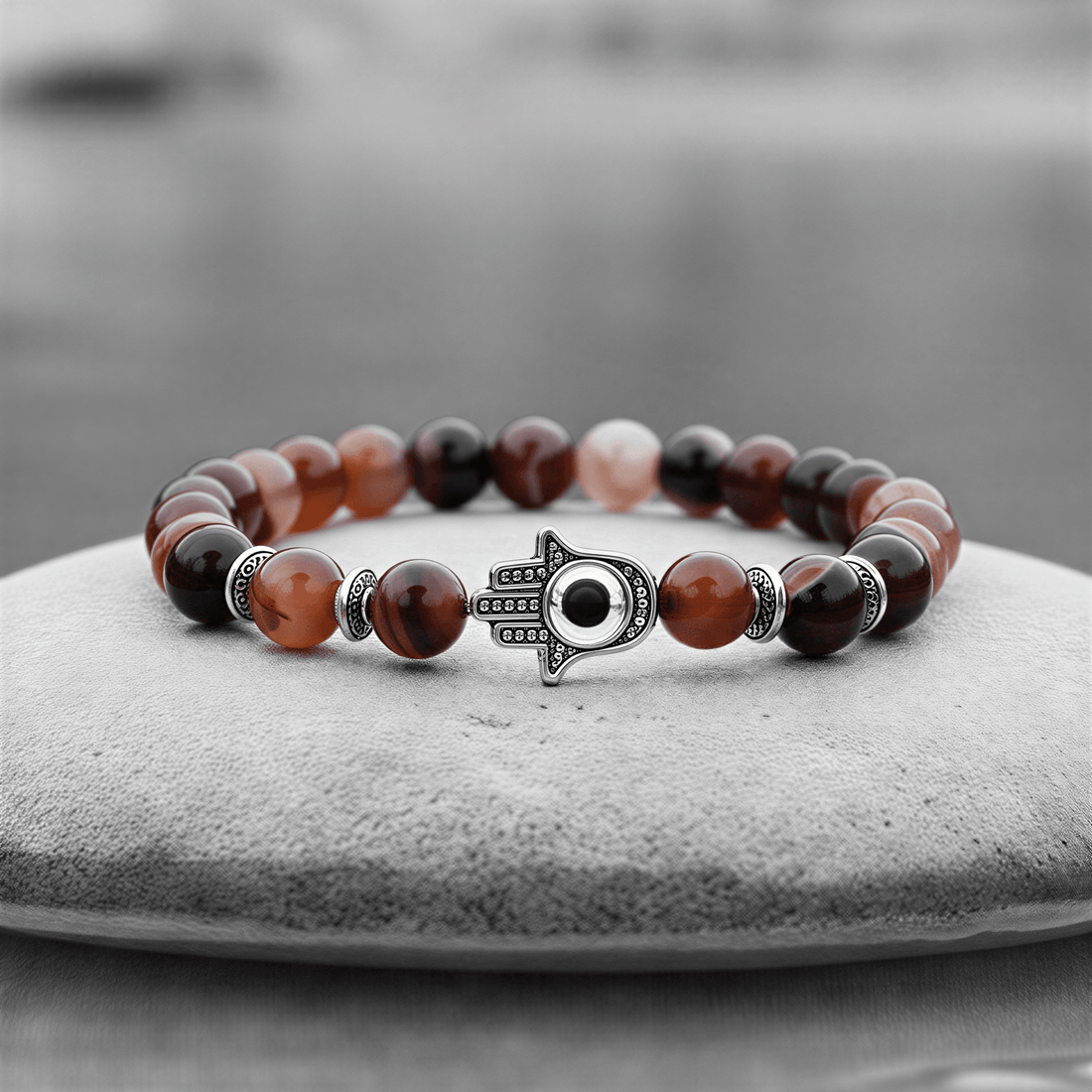 Rood edelstenen armband met agaat en hamsa handje liggend op steen in water | Red Lace Agate Hamsa