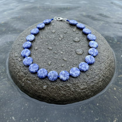 Blauwe handgeknoopte edelstenen ketting met blue spot jaspis stenen liggend op steen in water | Blue Spot Coin