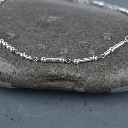 Zilveren edelstenen ketting met zilver edelstaal en hematiet stenen die het woord HAPPY in morse code weer geeft liggend op steen close up | Morse Code Happy Silver Hematite