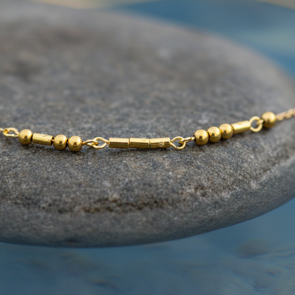 Gouden edelstenen ketting met goud edelstaal en hematiet stenen die het woord LOVE in morse code weer geeft liggend op steen close up | Morse Code Love Gold 