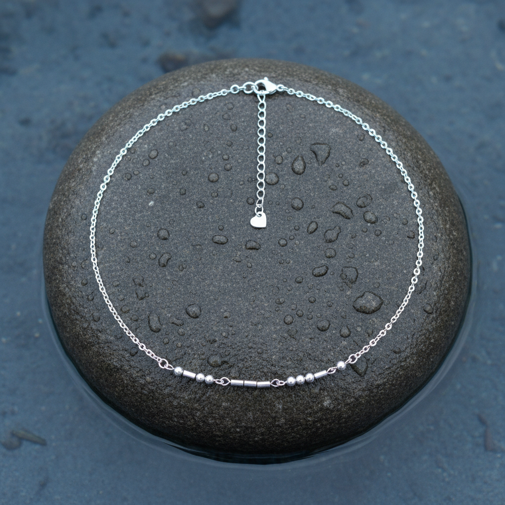 Zilveren edelstenen ketting met zilver edelstaal en hematiet stenen die het woord LOVE in morse code weer geeft liggend op steen in water | Morse Code Love Silver 