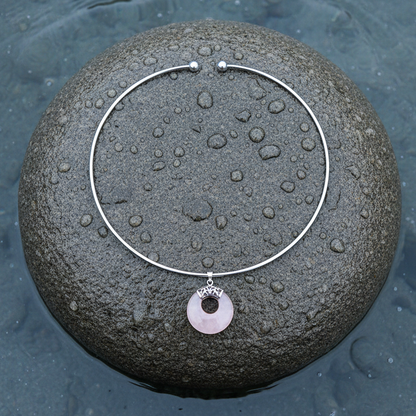 roze edelstenen ketting met rozenkwarts in vorm van donut liggend op steen in water | Rosé Quartz Donut