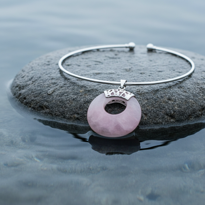 roze edelstenen ketting met rozenkwarts in vorm van donut liggend op steen close up | Rosé Quartz Donut