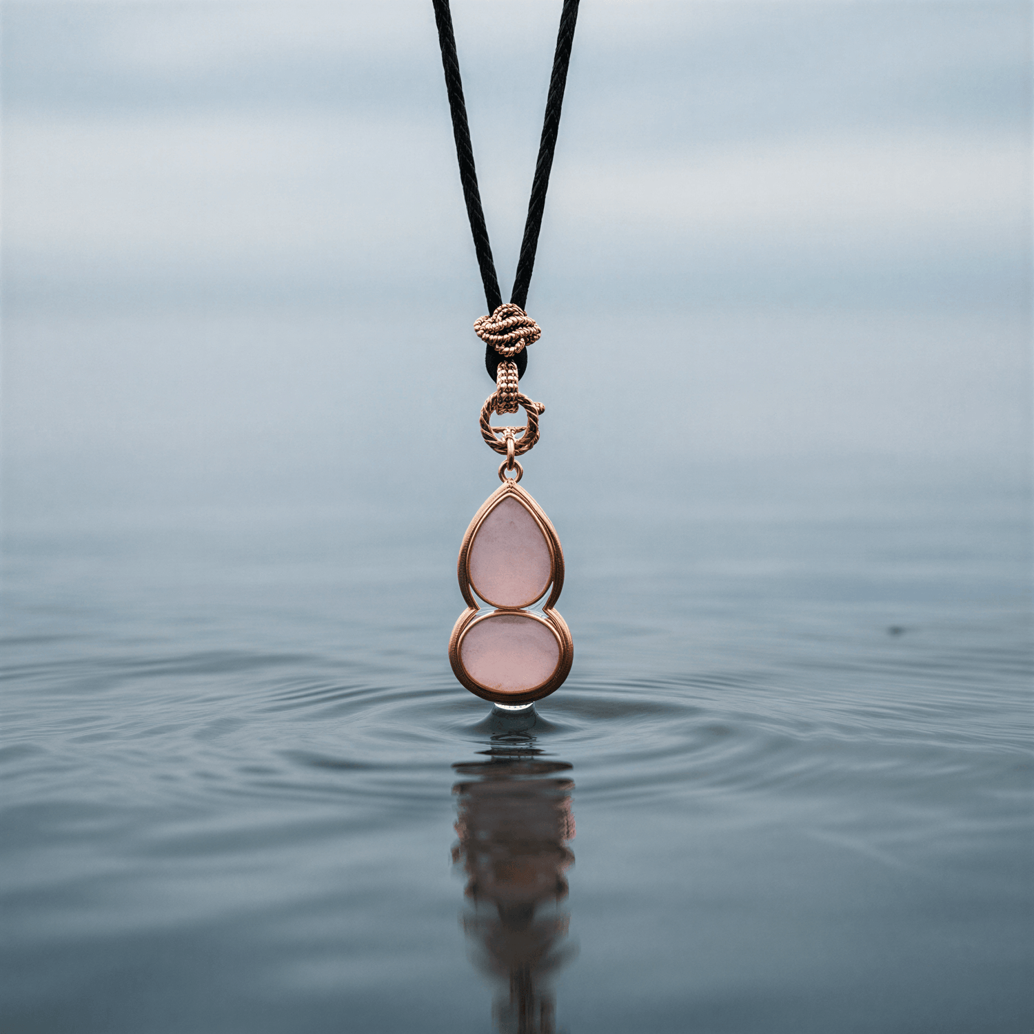 Roze edelstenen ketting met rozenkwarts en rosé goud hangend boven water | Rosé Quartz Gold