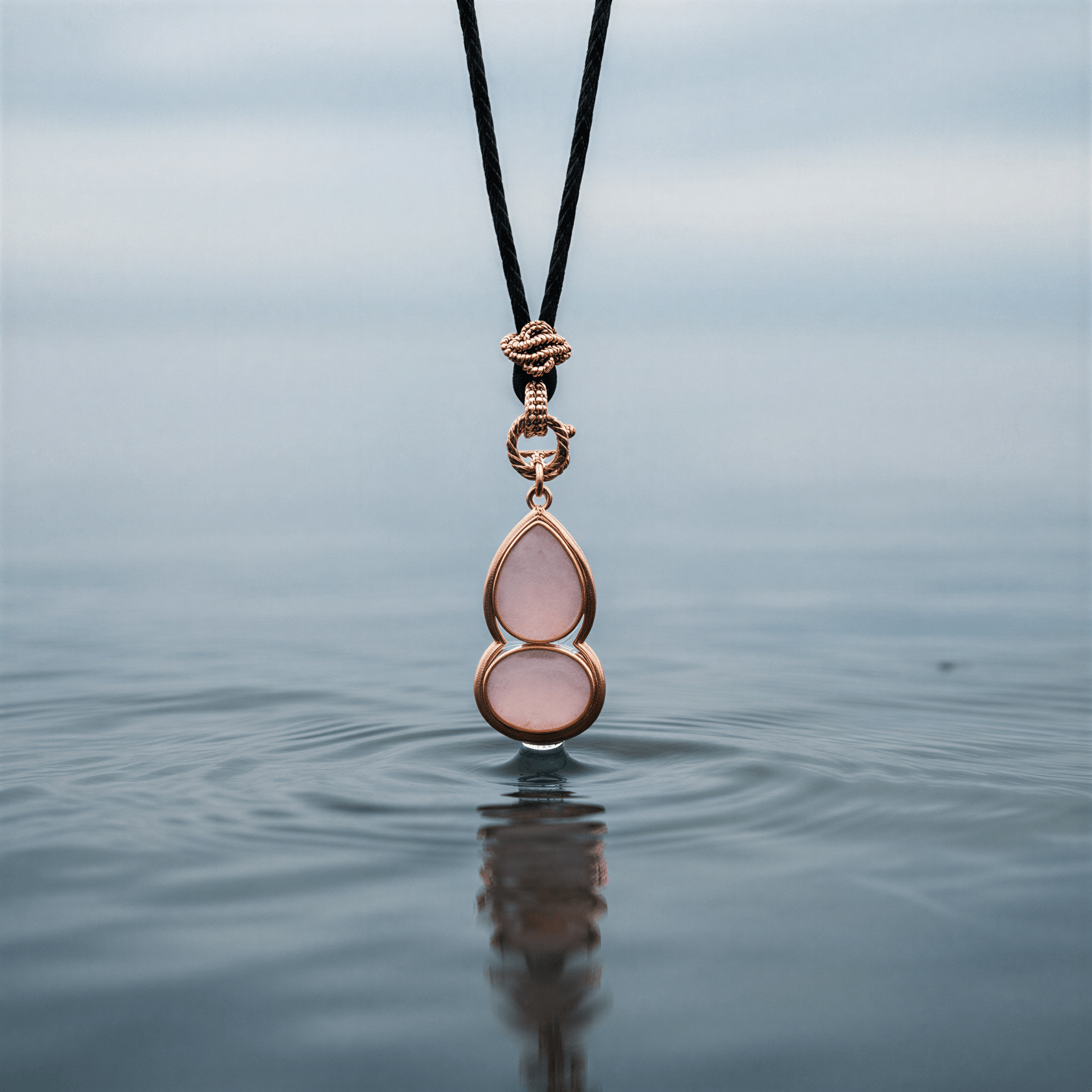 Roze edelstenen ketting met rozenkwarts en rosé goud hangend boven water | Rosé Quartz Gold