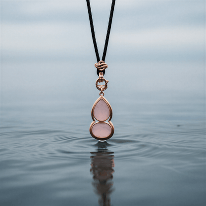 Roze edelstenen ketting met rozenkwarts en rosé goud hangend boven water | Rosé Quartz Gold