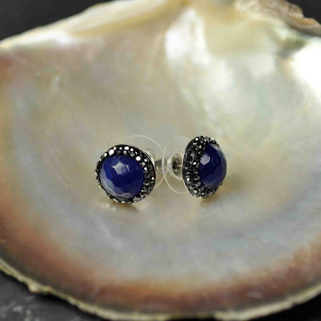 Donker blauwe edelstenen oorknoppen met stras steentjes en zilver edelstaal liggend in schelp | Black Bright Blue Agate