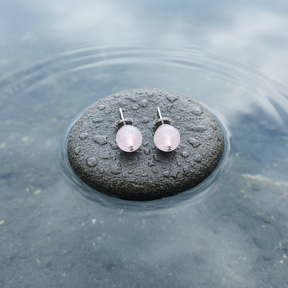Roze edelstenen oorbellen met rozenkwart, roze edelstenen oorknopjes liggend op steen bovenaanzicht | Bling Roze Quartz