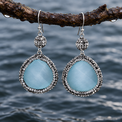 Licht blauwe edelstenen oorbellen met kattenoog, stras steentjes en sterling zilver (925) hangend aan takje boven water | Bright Blue Cat’s Eye