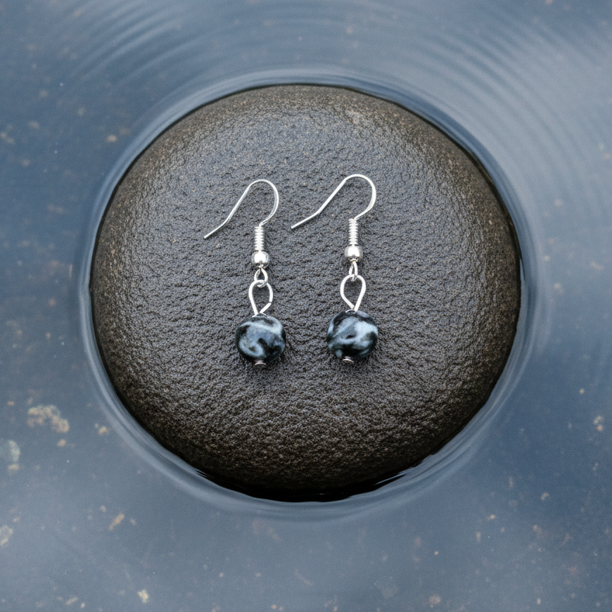 Edelstenen oorbellen met zwarte labradoriet en sterling zilver (925) liggend op steen | Dangling Black Labradorite