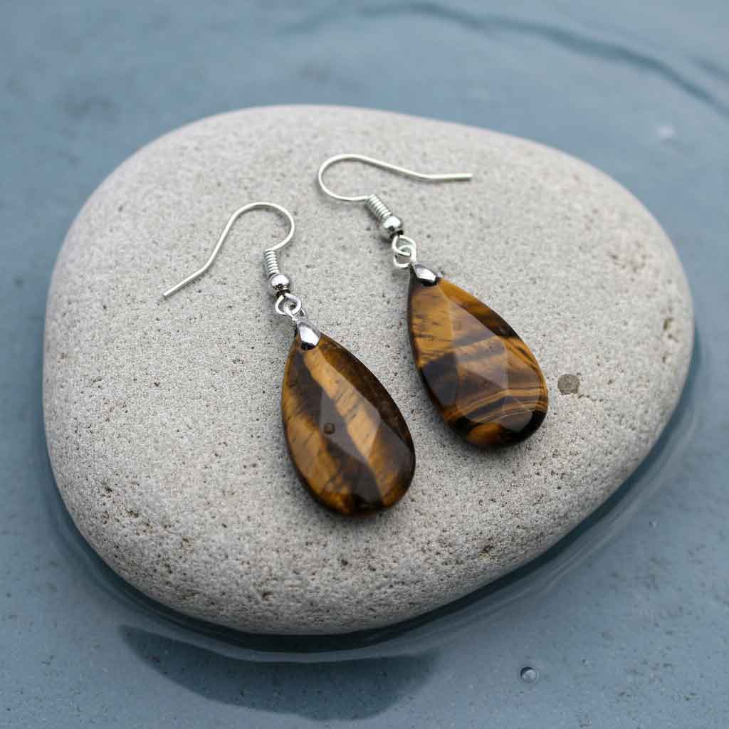 Bruine edelstenen oorbellen met tijgeroog en sterling zilver (925) liggend op steen in water | Facet Tiger Eye