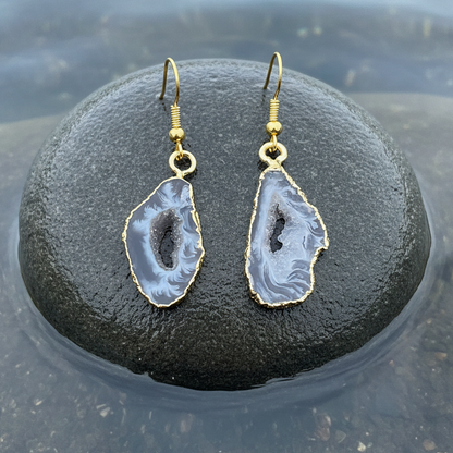 Grijze edelstenen oorbellen met ijskwarts en goud edelstaal liggend op steen in water | Gold Ice Quartz