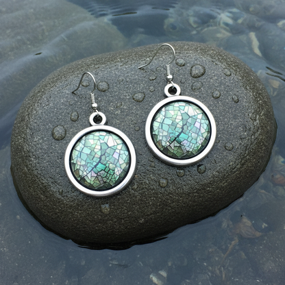 Parelmoeren oorbellen van groen blauw parelmoer en sterling zilver 925 liggend op steen in water | Blacklip Mozaik