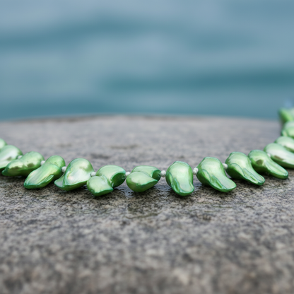 Handgeknoopte zoetwater parelketting met groene parels en sterling zilver (925) liggend op steen in water close up | Green Blister