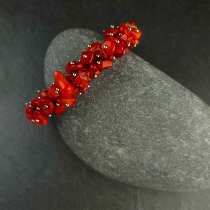 Dik rood koralen armband met stukjes koraal liggend tegen kei | Coral Chip