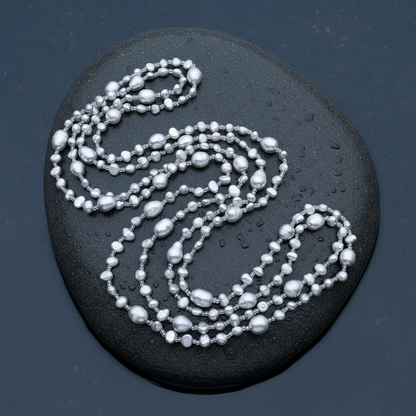 Lange zoetwater parelketting met grijze parels liggend op steen in water | Long Seed Bead Grey
