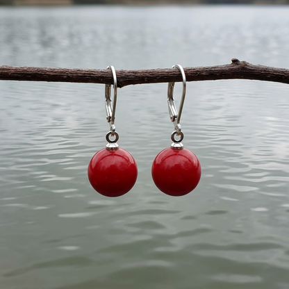 Rode mother of pearl parel oorbellen met zilver edelstaal hangend aan takje boven water | Scarlet