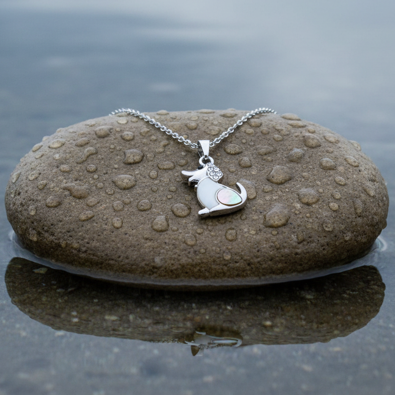 Parelmoeren ketting met hanger met wit en grijs parelmoer in de vorm van een hond met stras steentjes en zilver edelstaal liggend op steen | Shell Dog