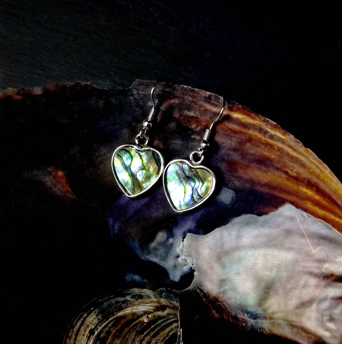 Parelmoeren oorbellen met abaloon in hartjes vorm en sterling zilveren oorbelhaakjes liggend in schelp