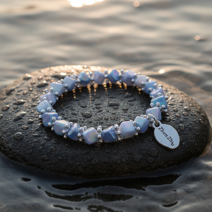 Blauw parelmoeren armband liggend op steen in water, elastisch | Shell Cube AB Blue