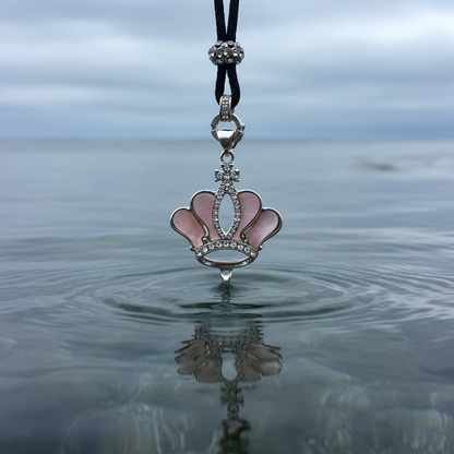 Detail van roze parelmoeren ketting met kroon en stras steentjes hangend boven water | Crown Pink