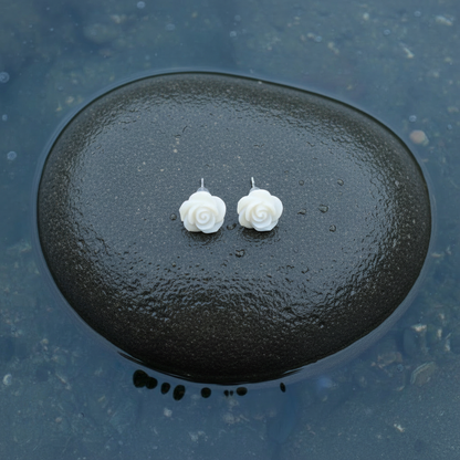 Witte parelmoeren oorknopjes in bloem vorm met sterling zilver 925 liggend op steen in water | White Shell Flower 7,5 mm