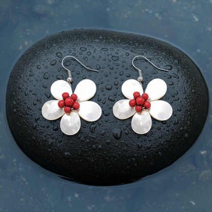 Parelmoeren oorbellen met wit parelmoer in de vorm van een bloem en zilver edelstaal liggend op steen in water | White Shell Flower Red Stone