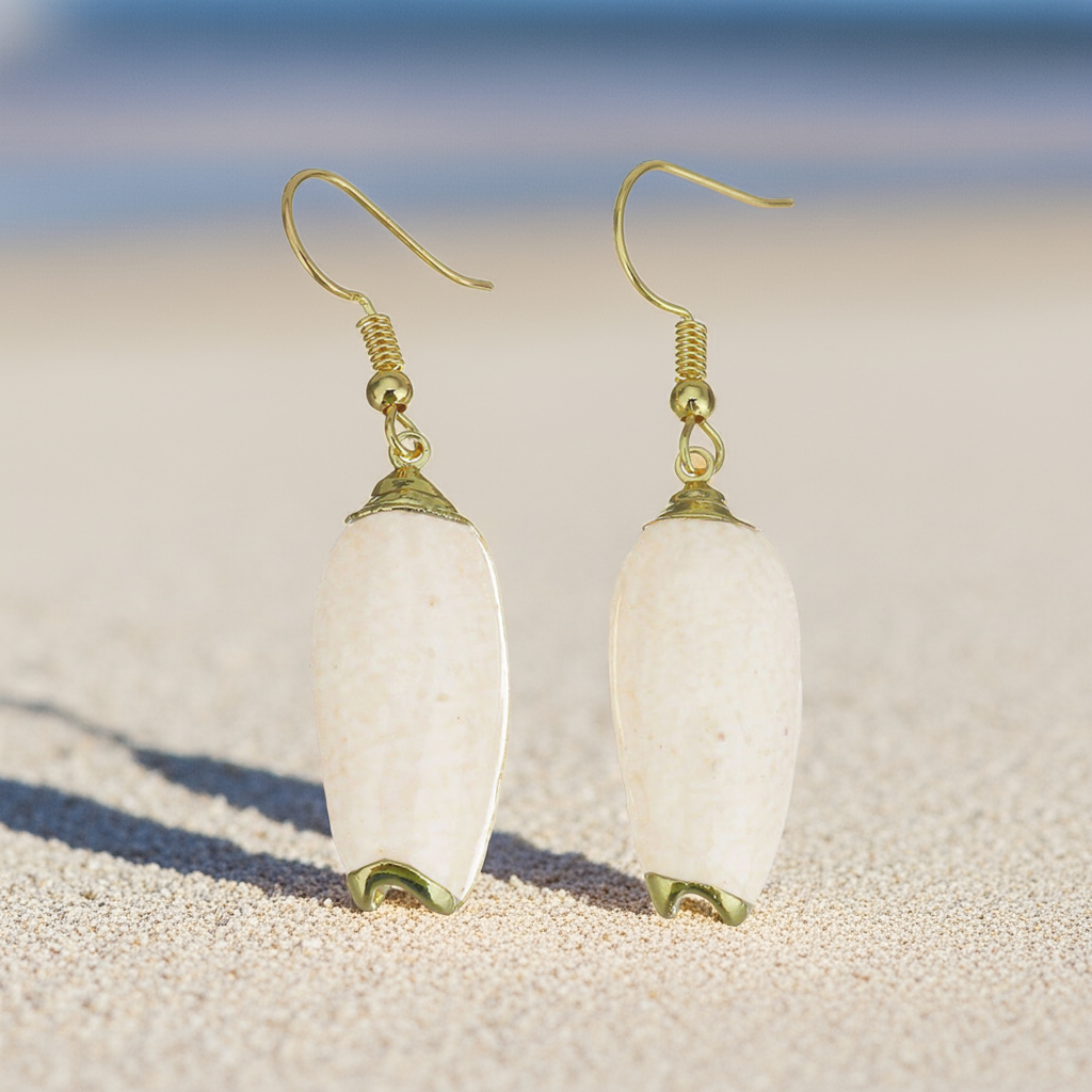 Schelpen oorbellen met beige schelp en goud edelstaal met achtergrond strand en zee | Pillar Seashell Gold