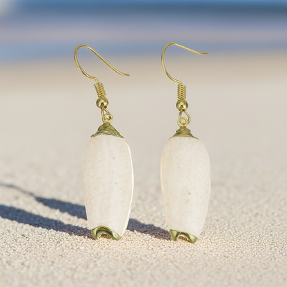Schelpen oorbellen met beige schelp en goud edelstaal met achtergrond strand en zee | Pillar Seashell Gold