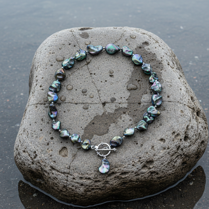 Donker blauw gekleurde parelmoeren schelpen ketting liggend op steen | Shell AB Blue