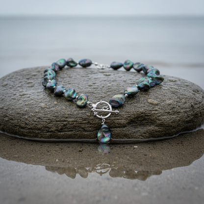 Donker blauw gekleurde parelmoeren schelpen ketting liggend op steen in het water | Shell AB Blue