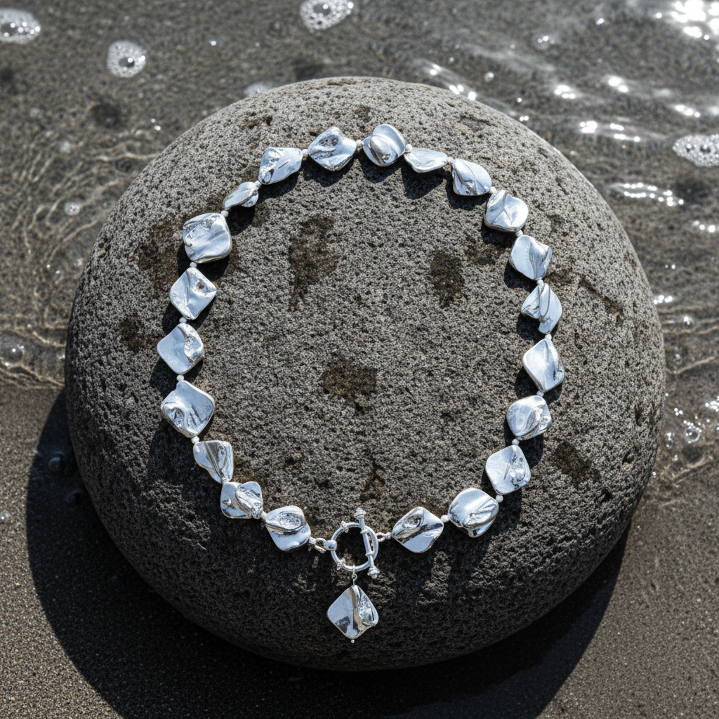 Zilver gekleurde parelmoeren schelpen ketting met hanger liggend op een steen | Shell Silver