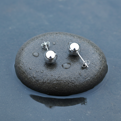 Verzilverde oorknopjes liggend op steen met voor en achterkant | Molly