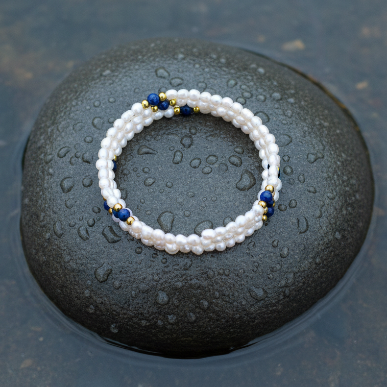 Wit zoetwater parel wikkelarmband met lapis lazuli liggend op steen in water | Agnes