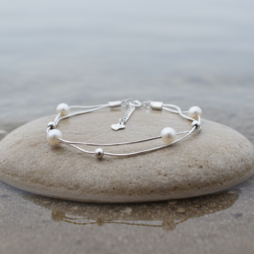 Wit zoetwater parel armband met sterling zilver (925) liggend op steen in water | Liv