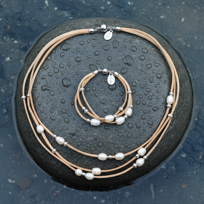 Multi-strand suède ketting en armband set met witte parels op natte grijze steen